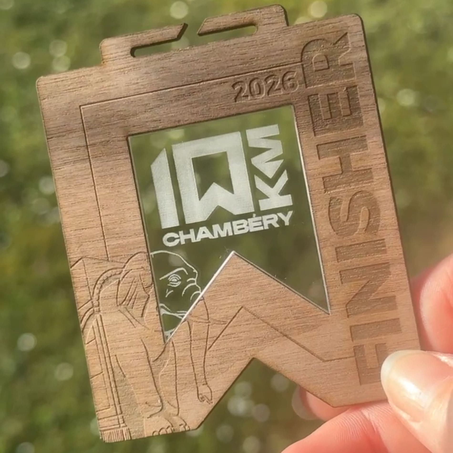 Médailles finisher bi-matériaux alignées sur une table en bois
